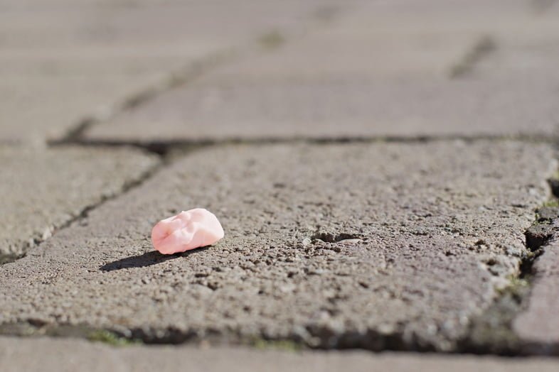 Розовая использованная жевательная резинка на тротуаре