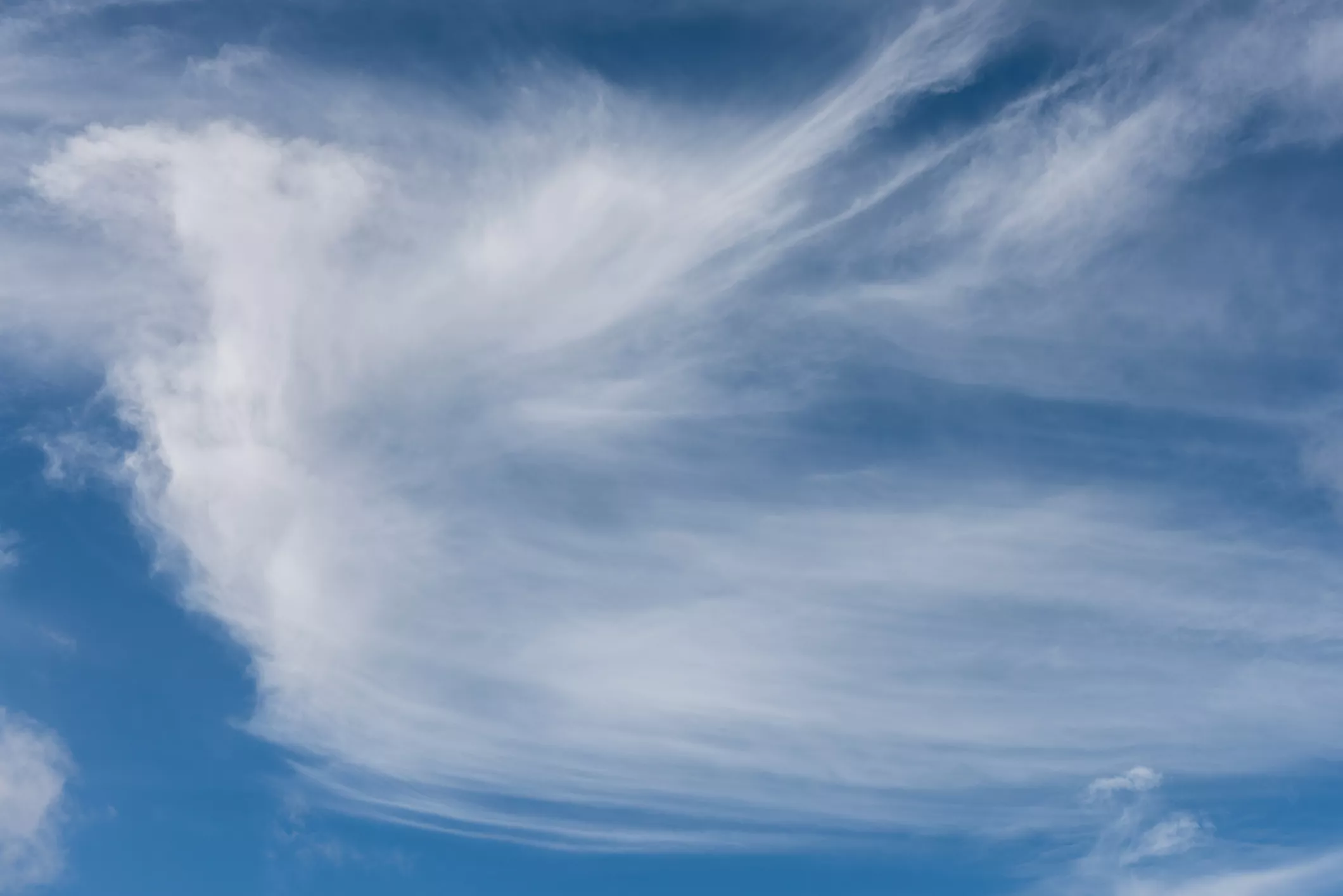 Тонкие перисто-слоистые облака высоко в голубом небе