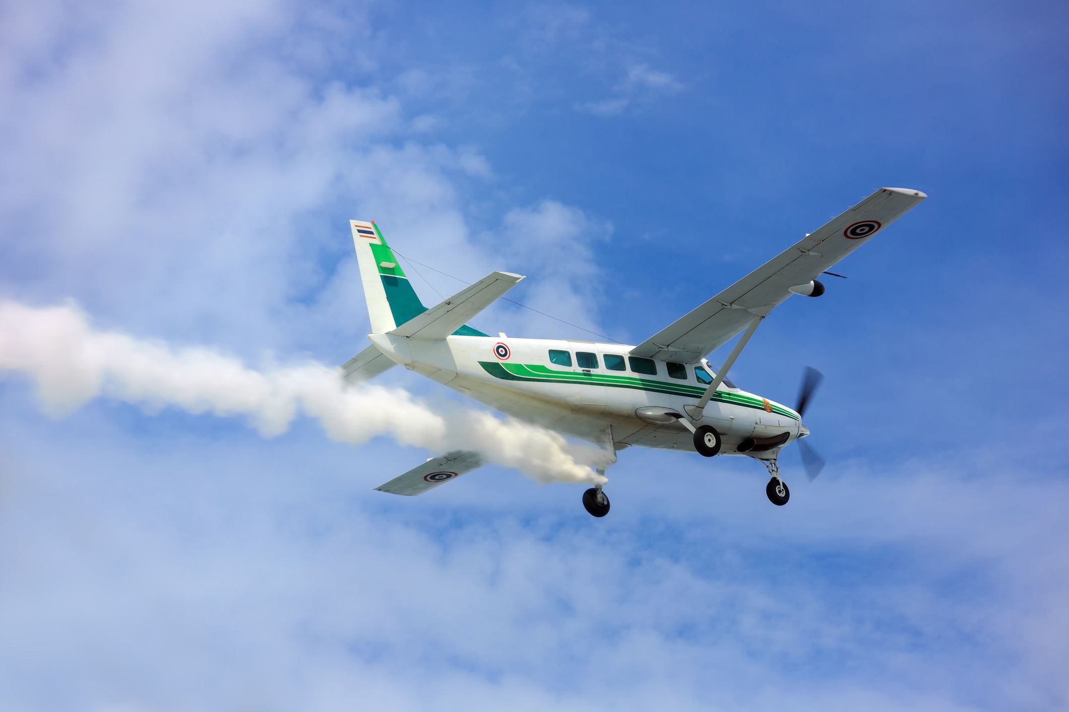 Крупный план турбовинтового самолета, распыляющего химикаты на облака в голубом небе