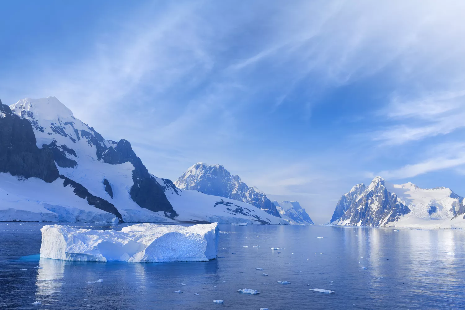 Ледяные горы окружают неподвижную голубую воду с небольшим ледником