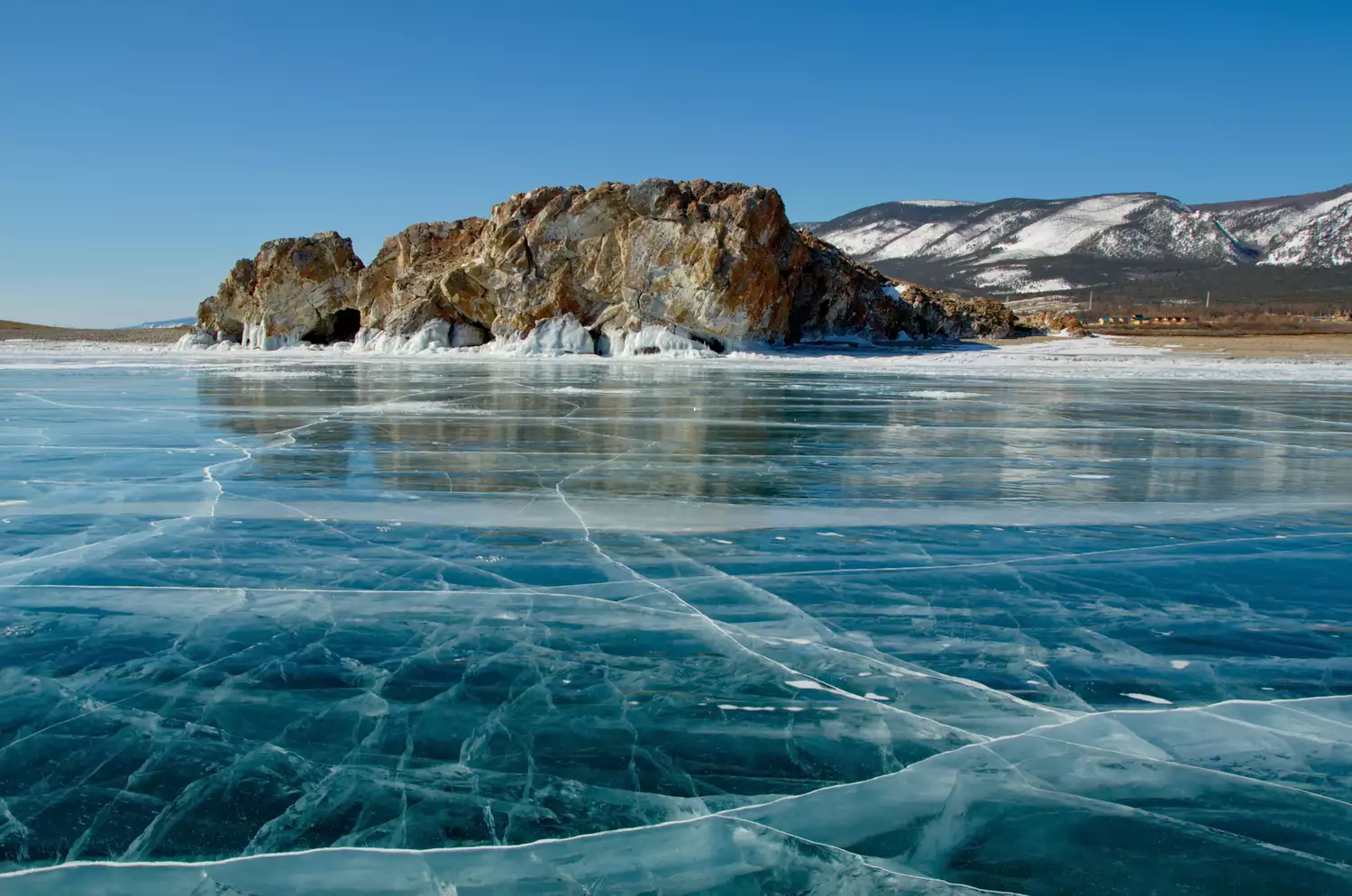 Прозрачное озеро с полосками льда, ведущими к изрезанной скальной структуре