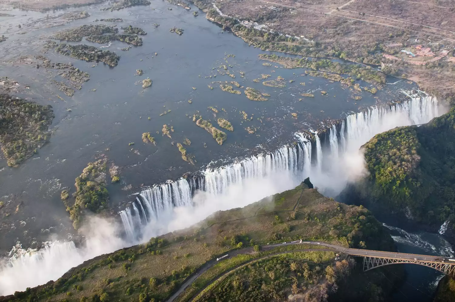 Вид с воздуха на длинный водопад, резко стекающий в пропасть, создавая туман