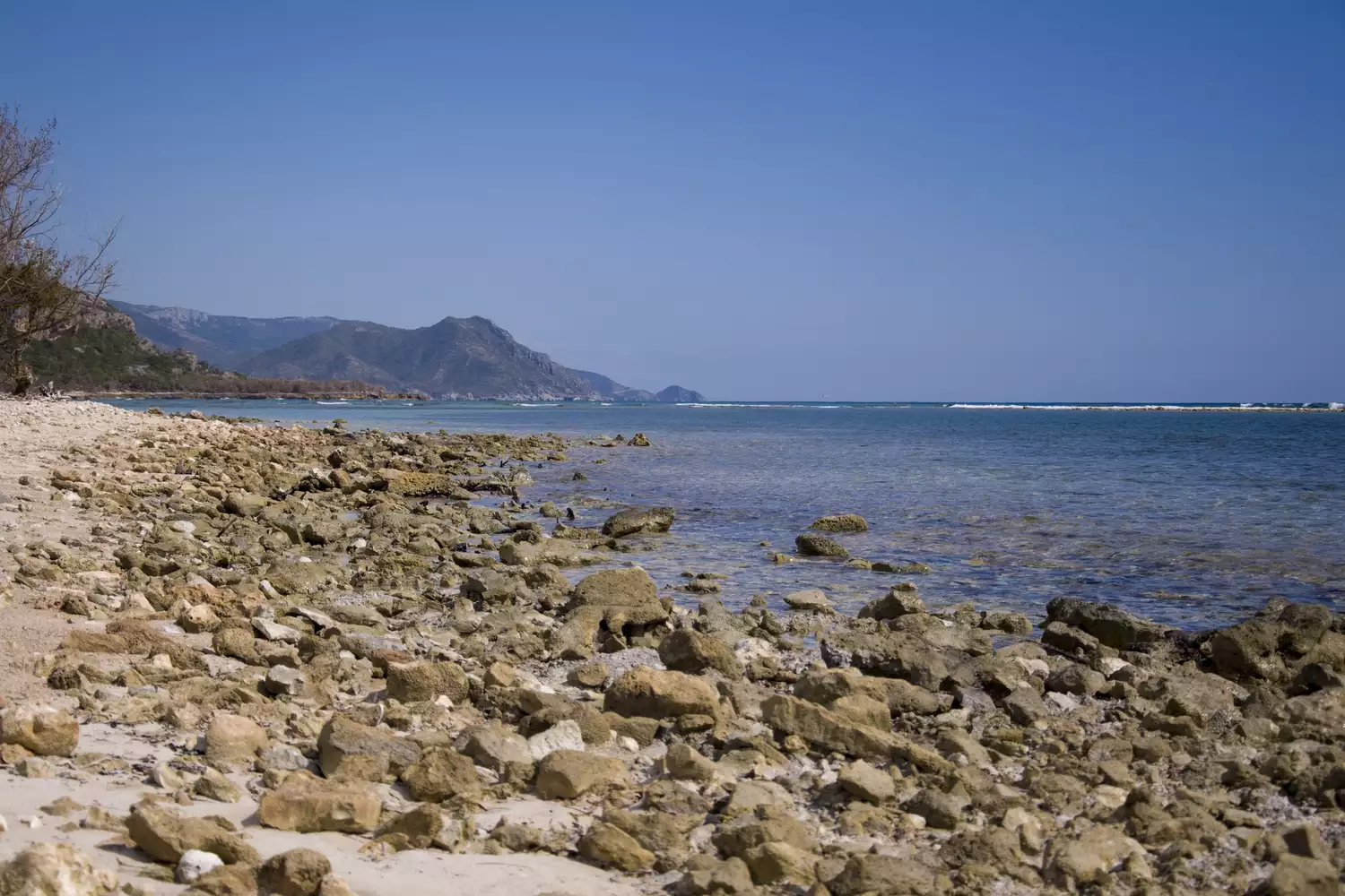 Пляж, покрытый большими камнями, у берега серо-голубого океана