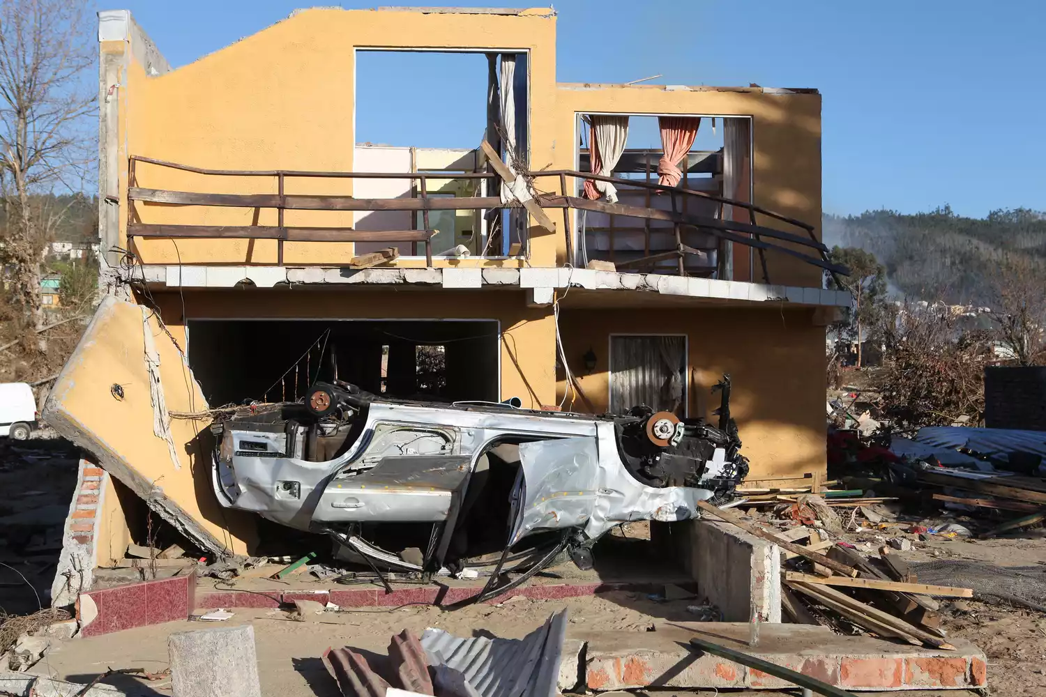 Перевернутый автомобиль и разрушенное здание после цунами в Чили