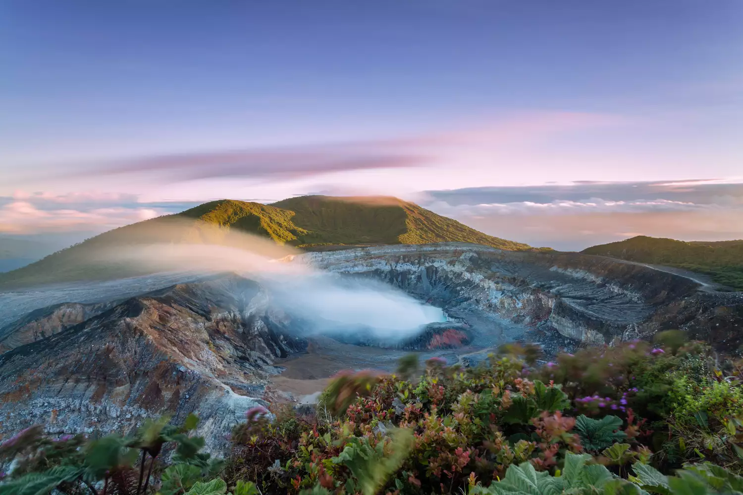 Вид с высоты на кратер в Коста-Рике, выбрасывающий дым на закате солнца