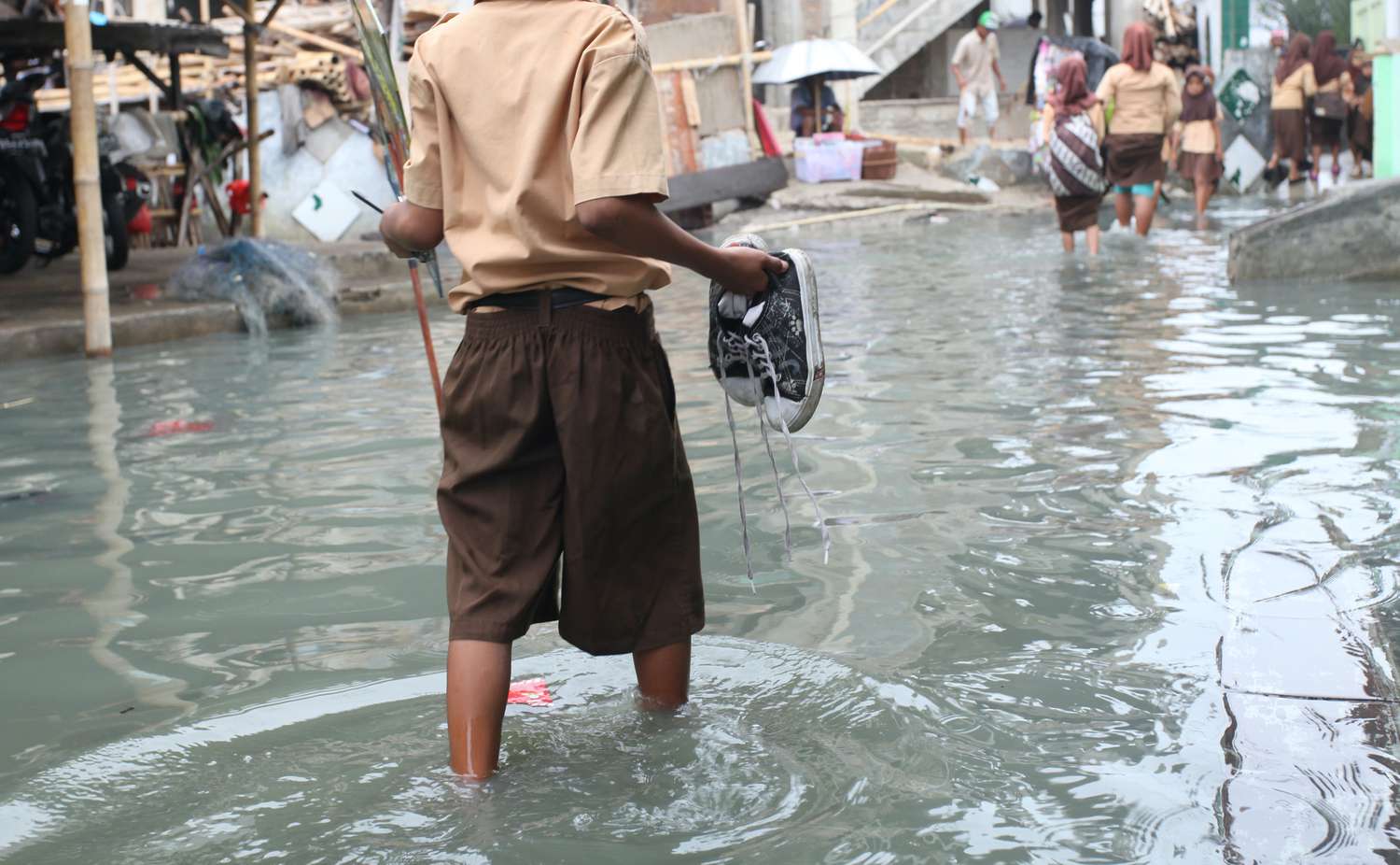 Ребенок пробирается по колено в воде во время наводнения