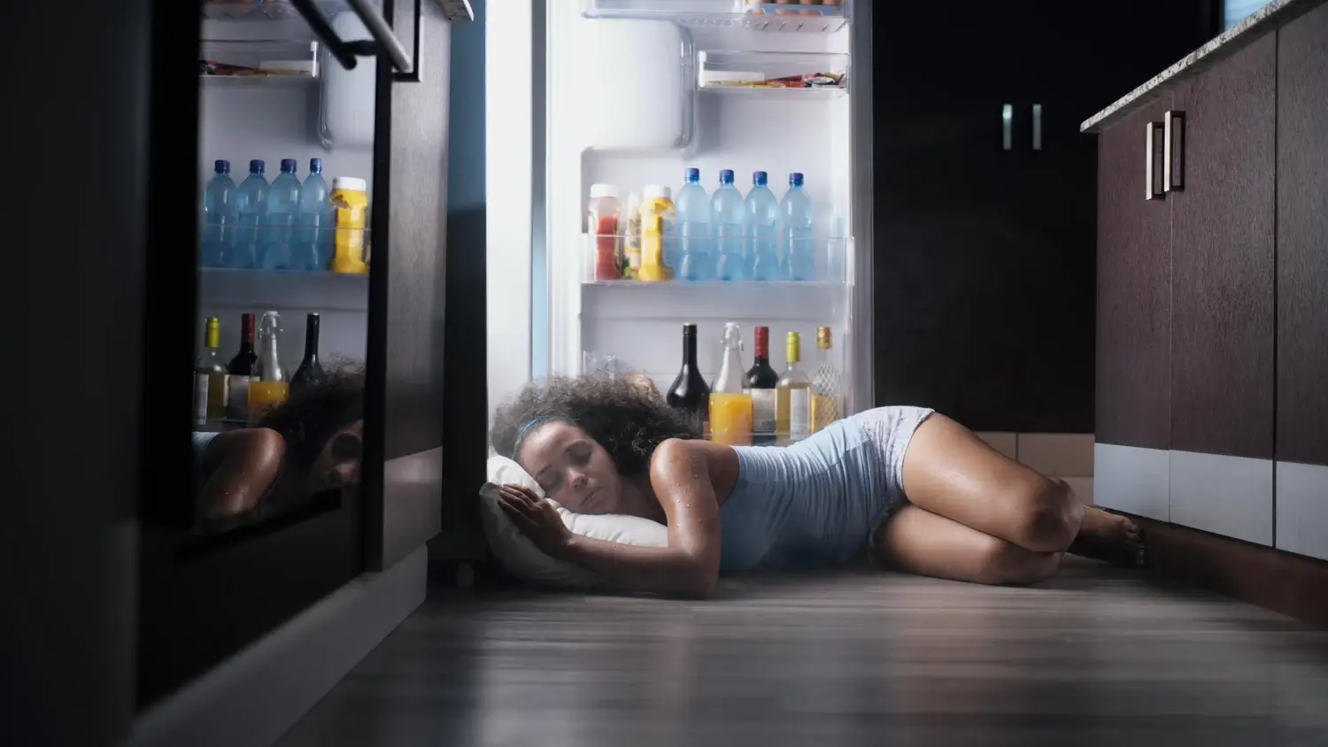 Женщина спит на полу, засунув голову в холодильник